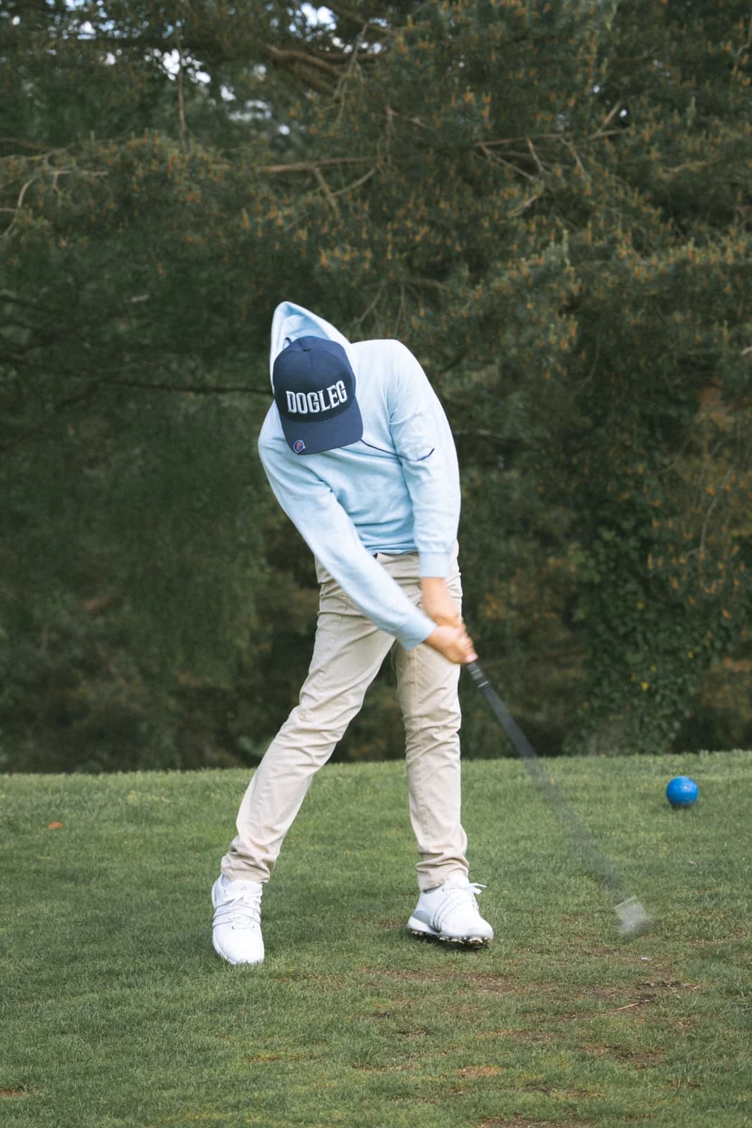 Junger Golfer, der auf dem Rasen des Platzes ein Eisen spielt