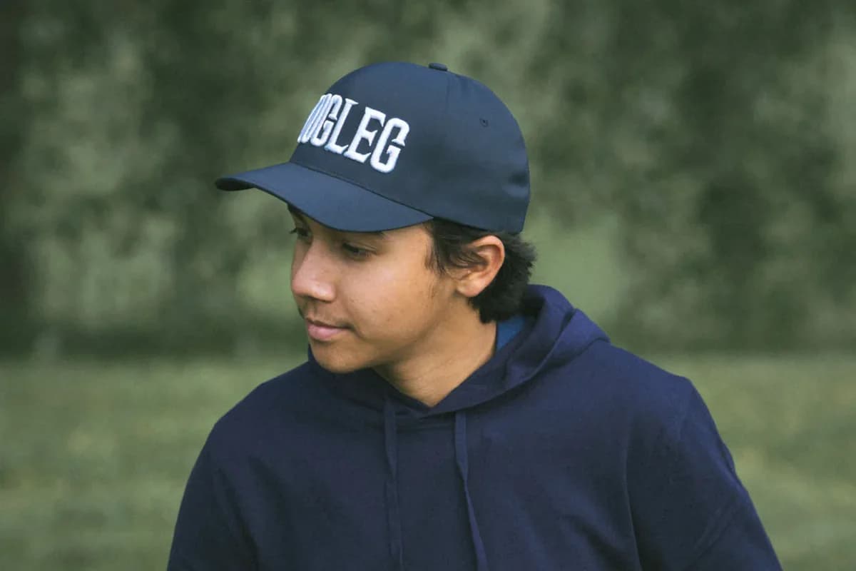 Junger Golfer im marineblauen Hoodie, einen Ball in der Hand