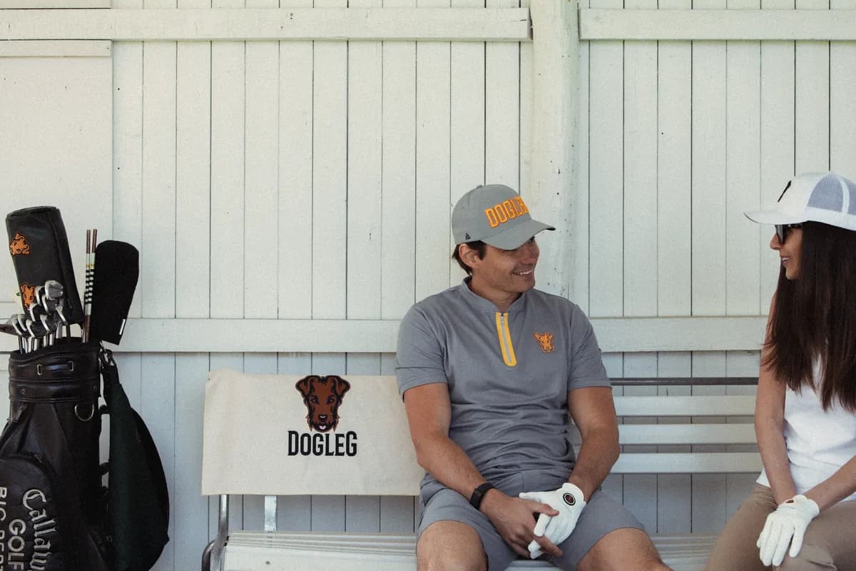 Two golfers, a man and a woman, sitting on a bench in front of the clubhouse