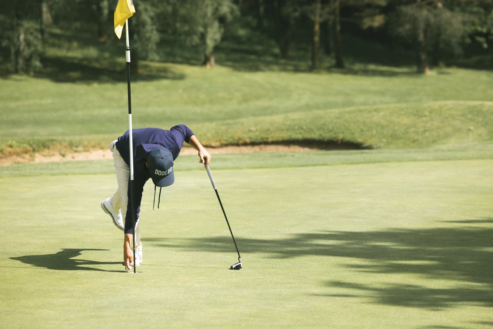 Golfer retrieving their ball from the hole on the green