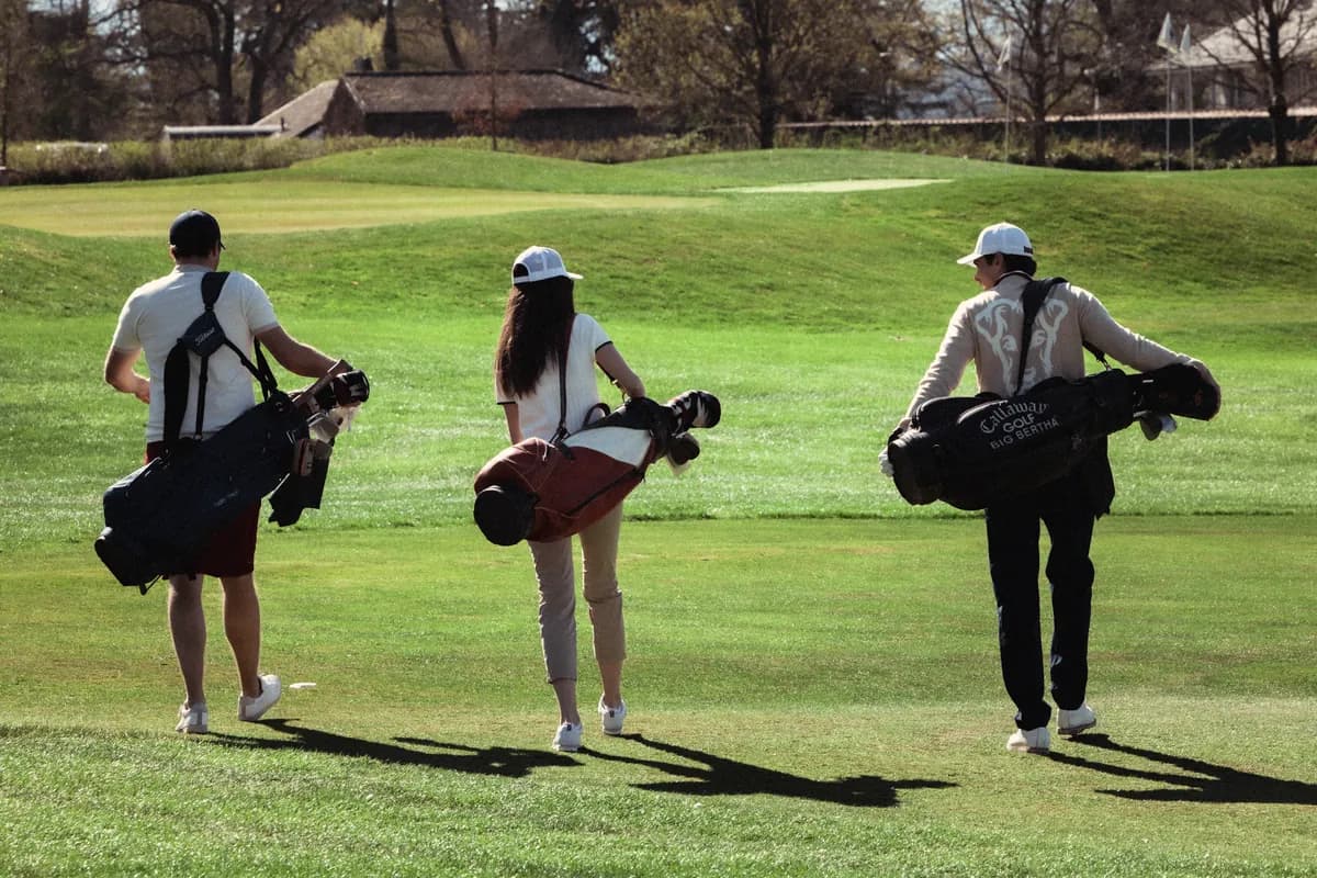 Tre golfisti, con la sacca in spalla, camminano sul fairway