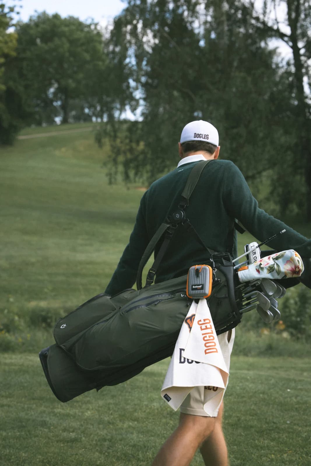 Golfspiller der bærer sin bag med et håndklæde hængende udenpå
