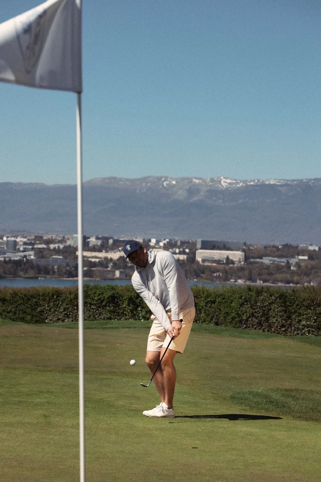 Golfspelare på greenen, nära flaggan, med bergen i bakgrunden